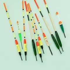 Różnokolorowe spławiki wędkarskie ułożone na jasnym tle.