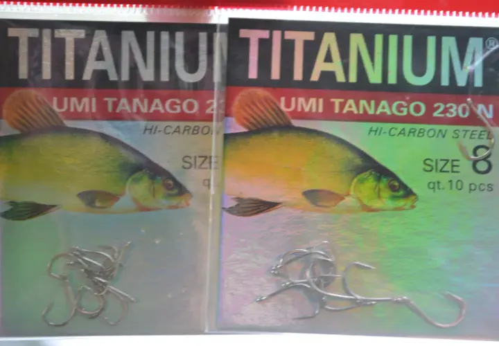 Dwa opakowania haczyków wędkarskich "TITANIUM UMI TANAGO 230N" z wizerunkiem karasia.